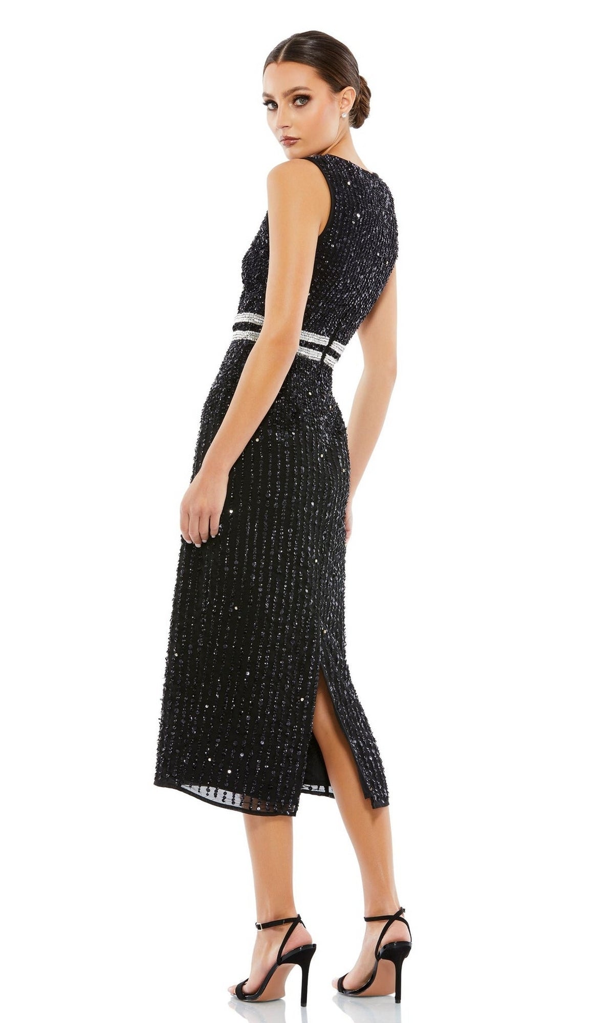 A woman models the Mac Duggal 10509 Short Sequin Wedding Guest Dress—sleeveless, black, with a white belt and back slit—paired with black high-heeled sandals against a white backdrop.